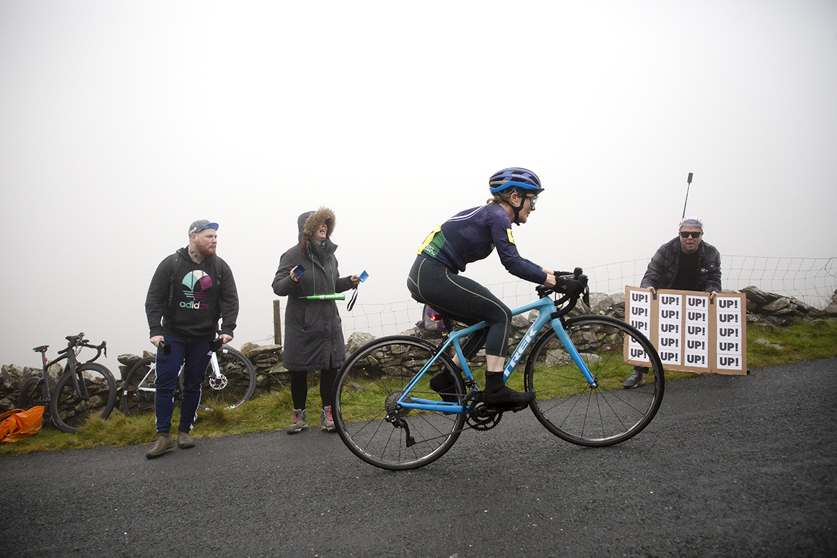 UK National Hill Climb Championships 2023 - A fan at the side of the climb holds a sign saying Up, Up, Up as Deborah John climbs