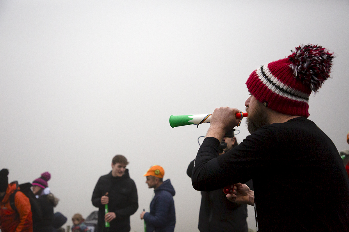 UK National Hill Climb Championships 2023 - A fan wearing a wooly bobble hat blows on a vuvuzela