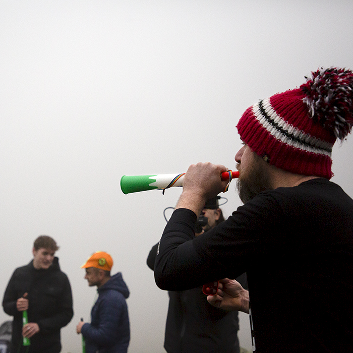 UK National Hill Climb Championships 2023 - A fan wearing a wooly bobble hat blows on a vuvuzela
